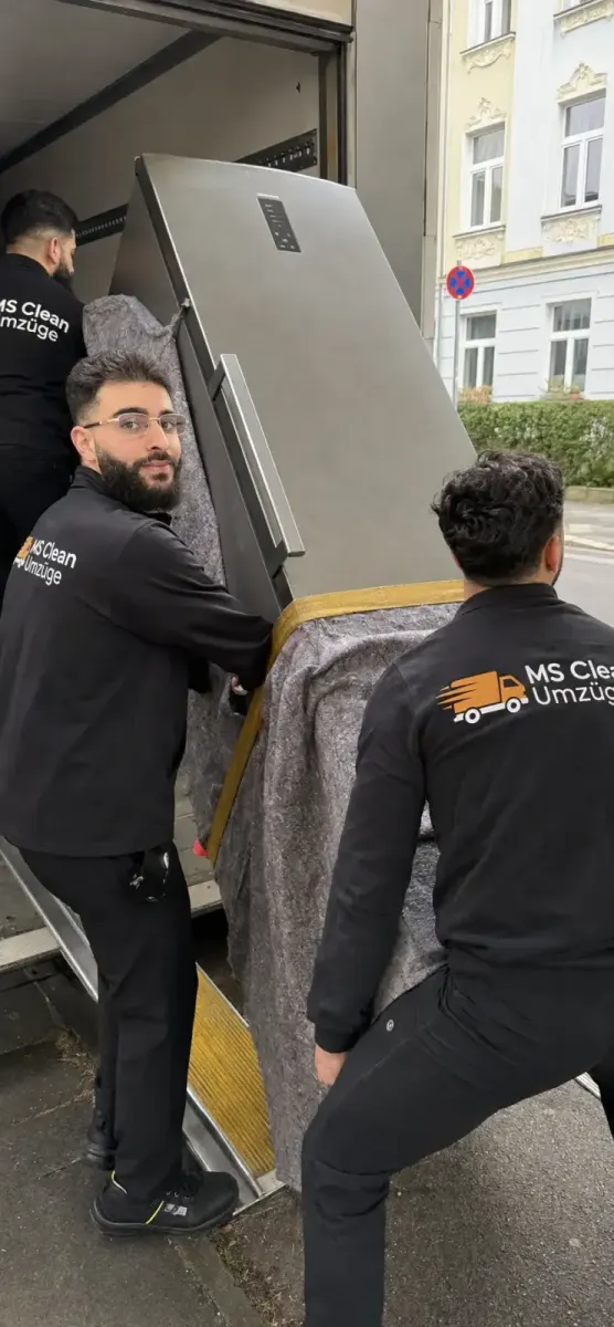 Umzugshelfer von Ms Clean verladen einen Kühlschrank in den Umzugswagen